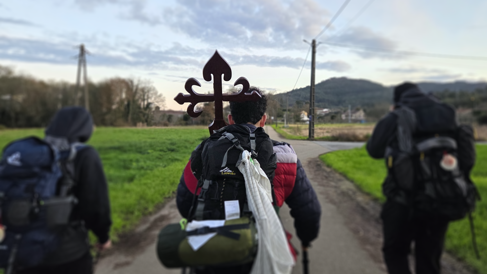 Pilgrims walking along the Camino de Santiago with the St. James cross